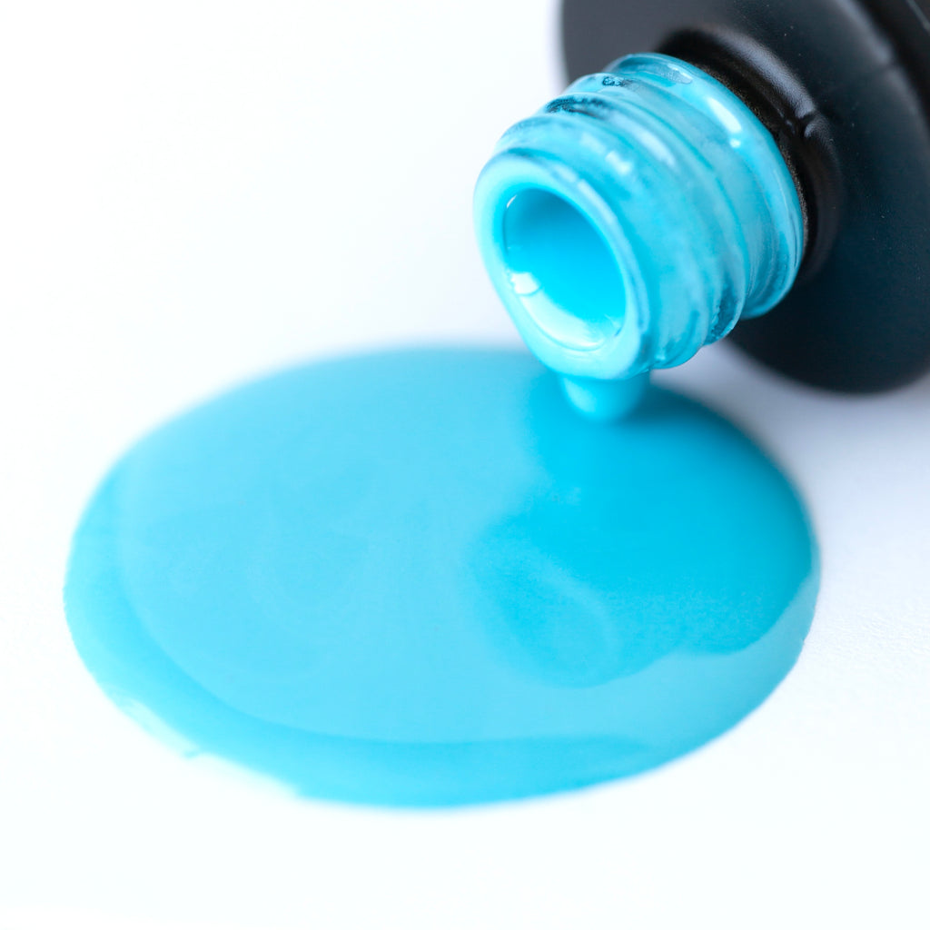 A round bottle of Baby Blues gel nail polish is shown against a white background. The black label features the words 'Nails Mailed' in white font. The light blue shade of the polish is visible through the clear glass bottle, which has a black cap with a brush applicator sticking out of it. The glossy finish of the polish catches the light, making the color appear even more radiant.