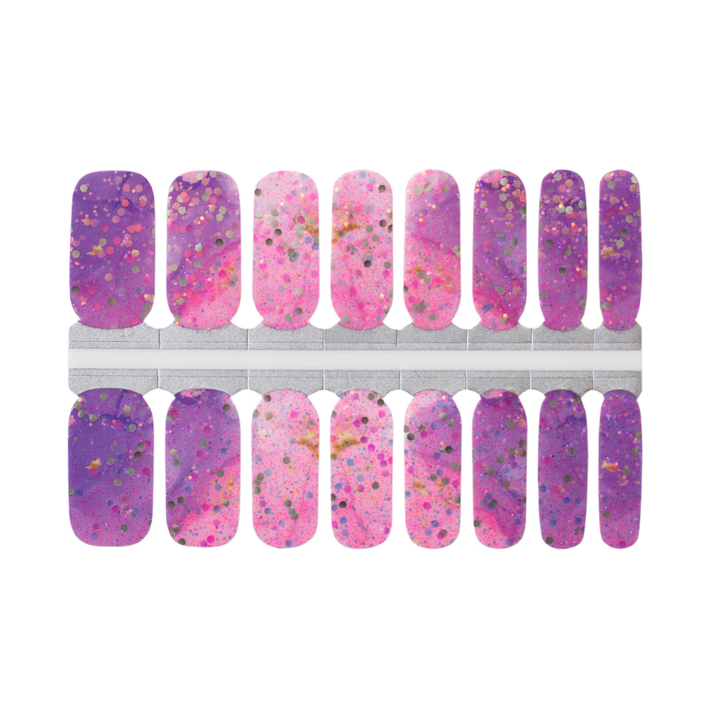 Close-up photo of purple and pink cosmic-themed Aurora Shine nail wraps with large gold glitter accents on a white background