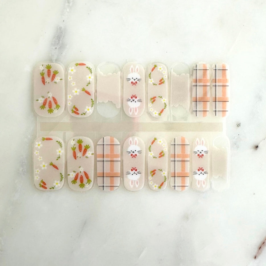 A close-up photo of 'Bunny Hop' FlexiGel nail wraps featuring a mix of pastel colors, negative space elements, and adorable bunny and carrot graphics, perfect for celebrating Easter and springtime