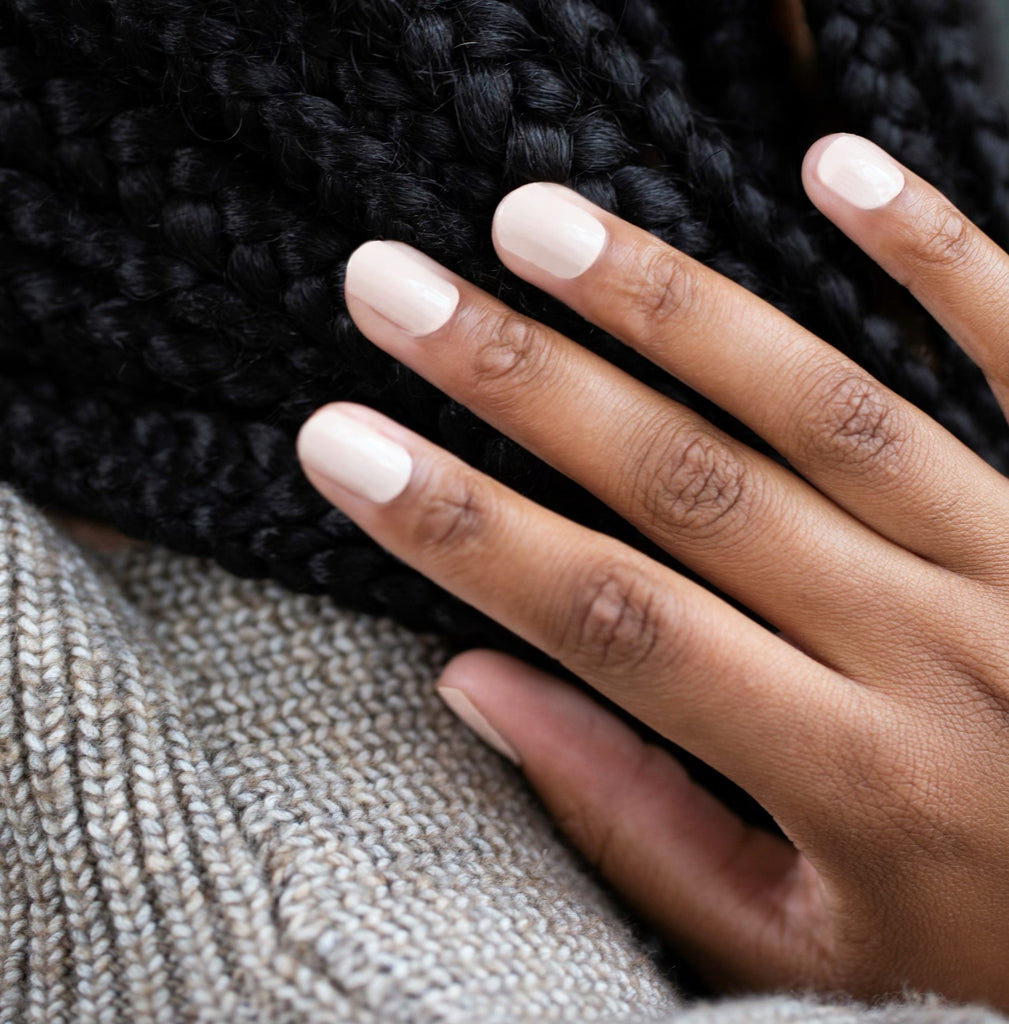 Image of a model's hand adorned with Nude nail wraps by Nails Mailed, showcasing the classic light tan color that gracefully complements the skin tone. The elegant, subtle shade offers a natural and sophisticated appearance, ideal for achieving a salon-quality nude look at home.