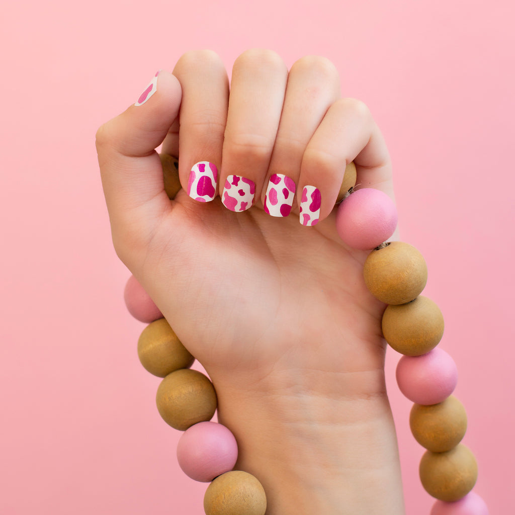 Pink Cow Print nail wraps on a hand