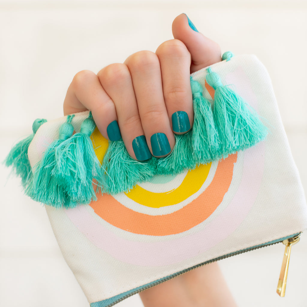 This teal nail wrap is reminiscent of an ocean bay blue and is shown on a hand holding a wallet