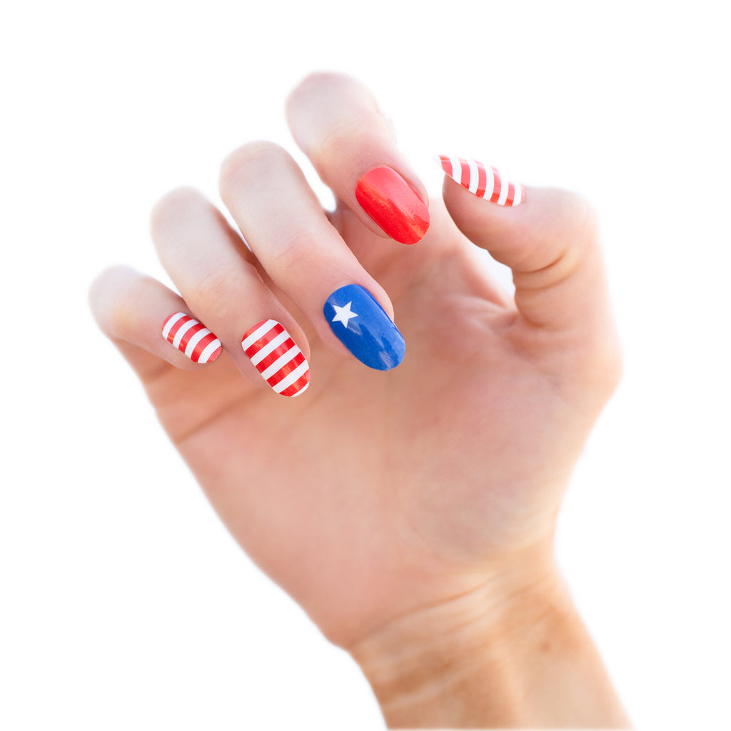 A model's hand featuring "USA Nail Wraps" with minimalist aspects of the American flag. The nail wraps have a red, white, and blue color scheme and are shown on the fingers and nails of the model's hand.