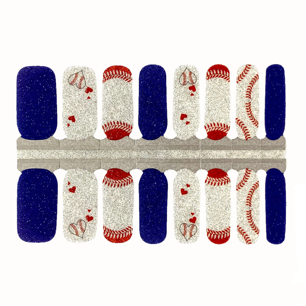 Close-up photo of baseball-themed nail wraps with red, white, and blue designs and a glitter base, displayed against a white background.