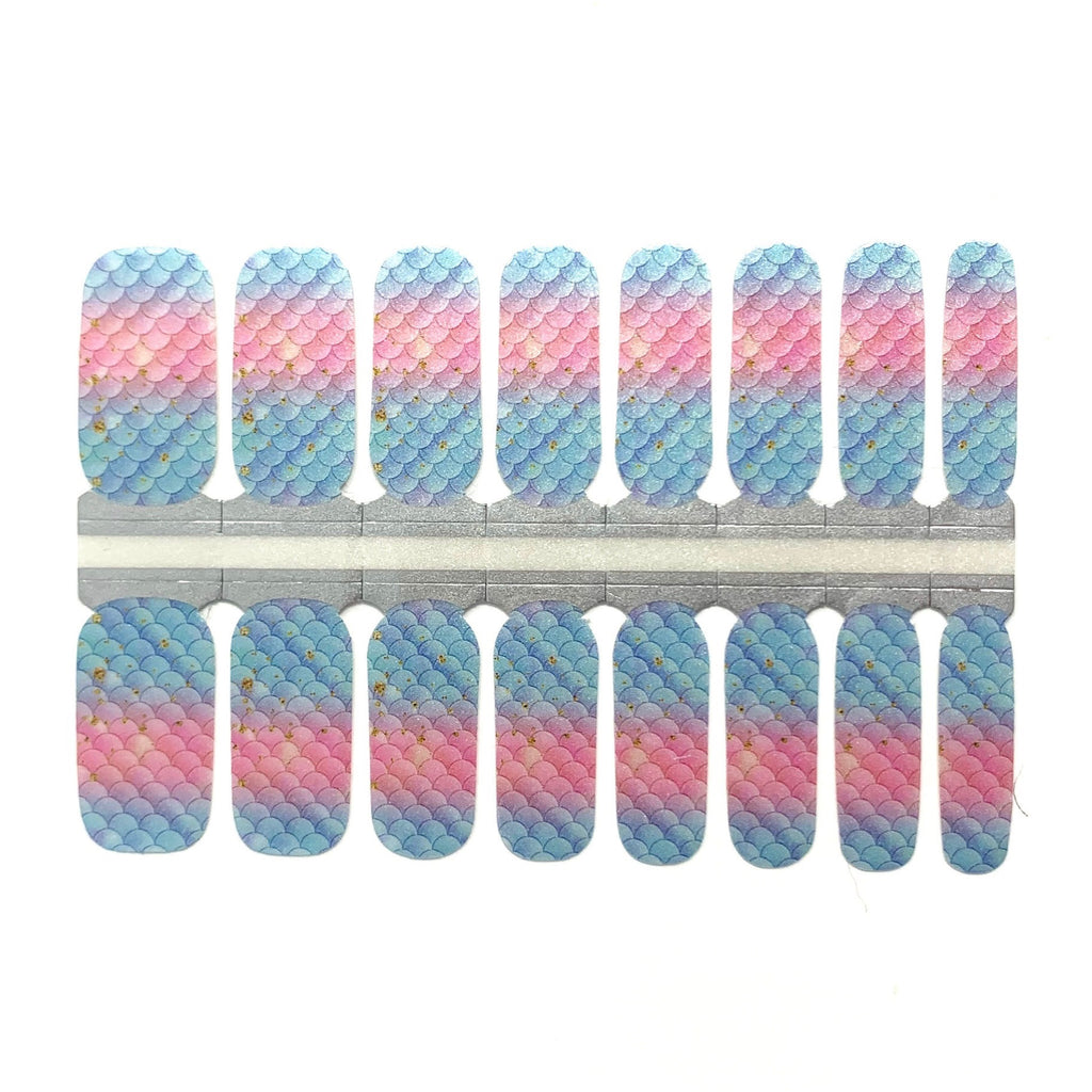 A photo of the Mermaid Nail Wraps against a white background. The rectangular wraps are aligned next to each other, and each one features a shimmery blue and pink fish scale pattern. The photo is well-lit and provides a clear view of the product. The wraps have a glossy finish and are slightly curved to fit the shape of a fingernail. These eco-friendly wraps are easy to apply and chip-resistant, providing a long-lasting and stylish look.