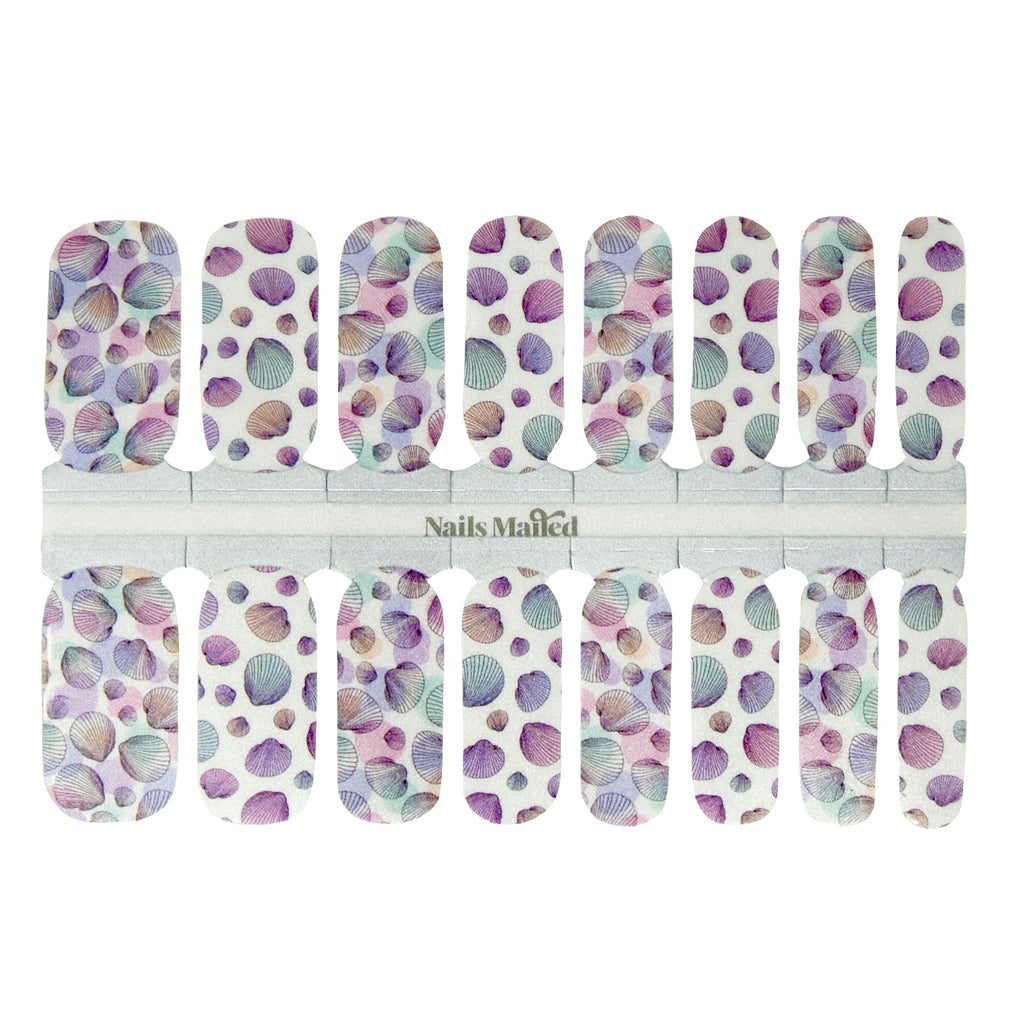 Seashells nail wraps against a white background, showcasing delicate ocean-inspired graphics in a captivating color palette of muted blues, purples, teals, and grays for a tranquil and unique style.