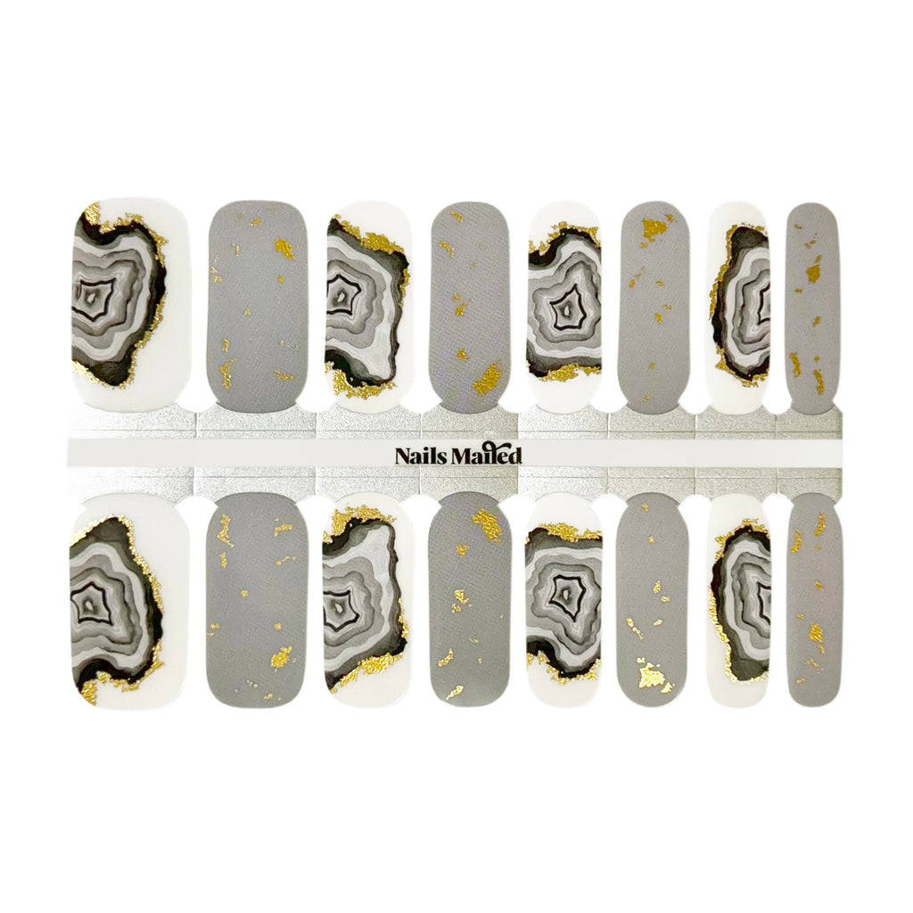 Crystal Clear nail wraps against a white background, displaying intricate black and gray geode graphics with gold foil accents on clear and gray bases for a sophisticated and exclusive style.